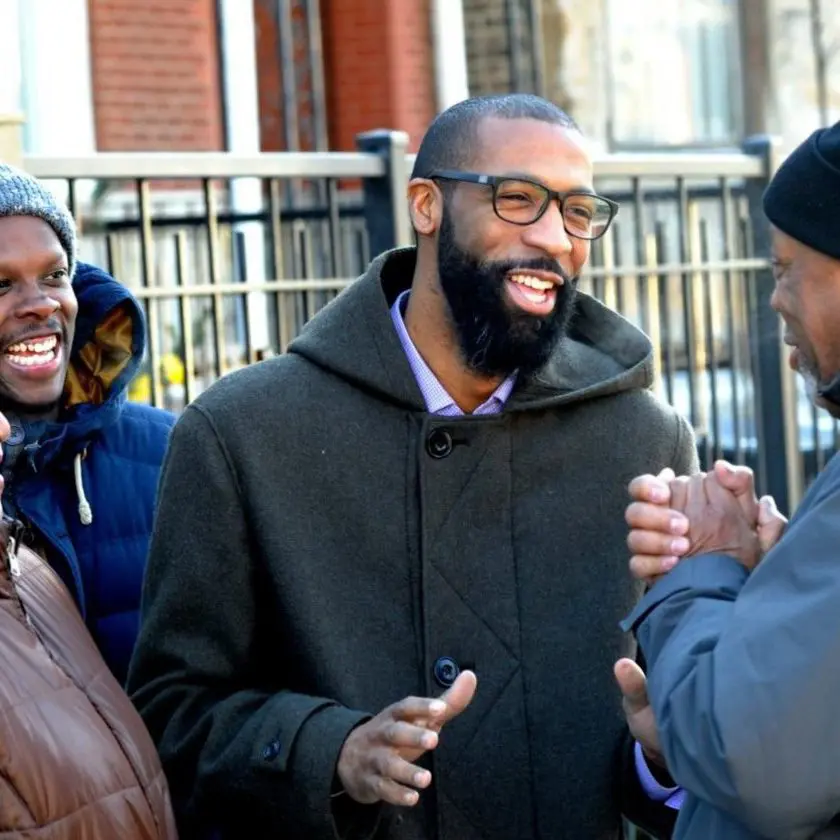 a man with a beard and eyeglasses talking to other people