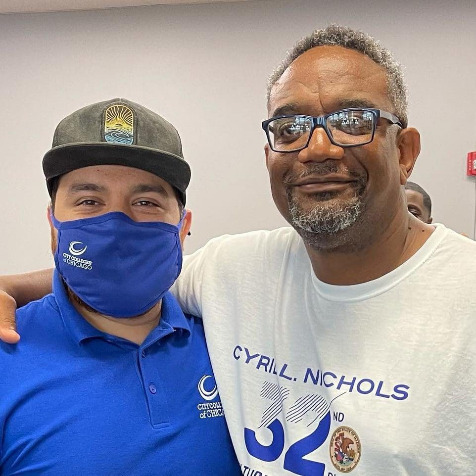 a person wearing a face mask and a cap next to a man with a beard and eyeglasses