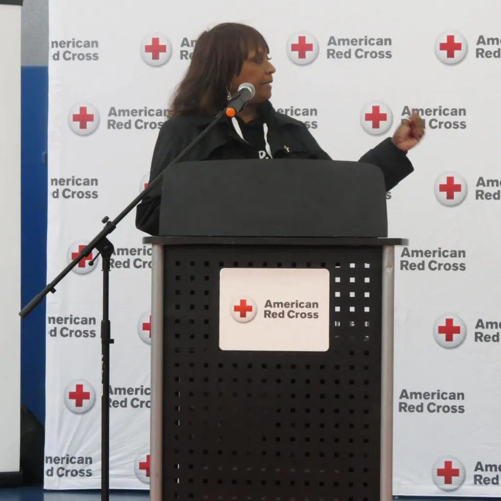  a woman in a black top speaking at an American red cross event