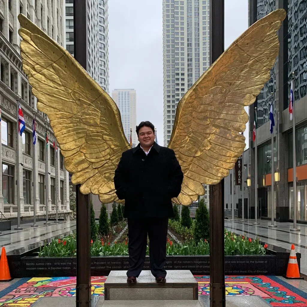 a man standing in front of a golden wing statue