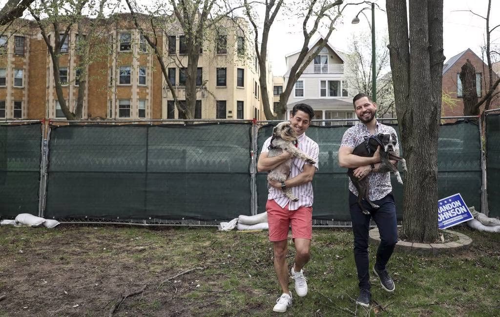 Kevin Romero, left, and his husband, Philip Maziarz, hold their dogs Parker and Wickett outside the home they're renovating in Uptown on April 15, 2023, in Chicago. (Shanna Madison / Chicago Tribune)
