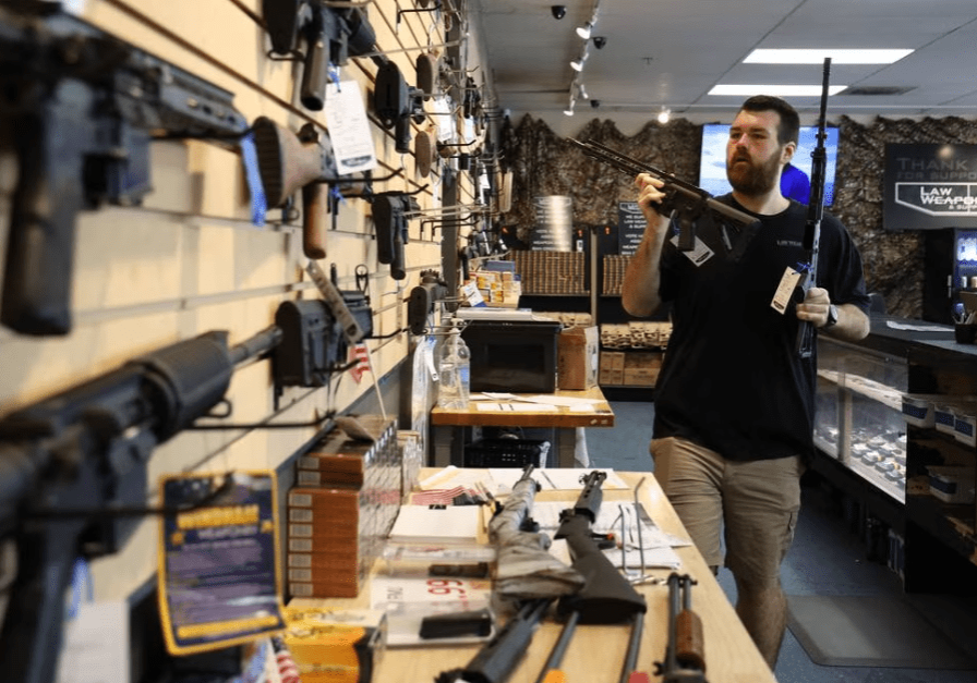 An employee at Law Weapons & Supply in Naperville rearranges guns at the store on May 11, 2023. The U.S. Supreme Court on Wednesday denied a request from a Naperville gun store owner to block a city ordinance and Illinois law banning the sale of certain high-powered firearms and high-capacity ammunition magazines. (Stacey Wescott/Chicago Tribune)
